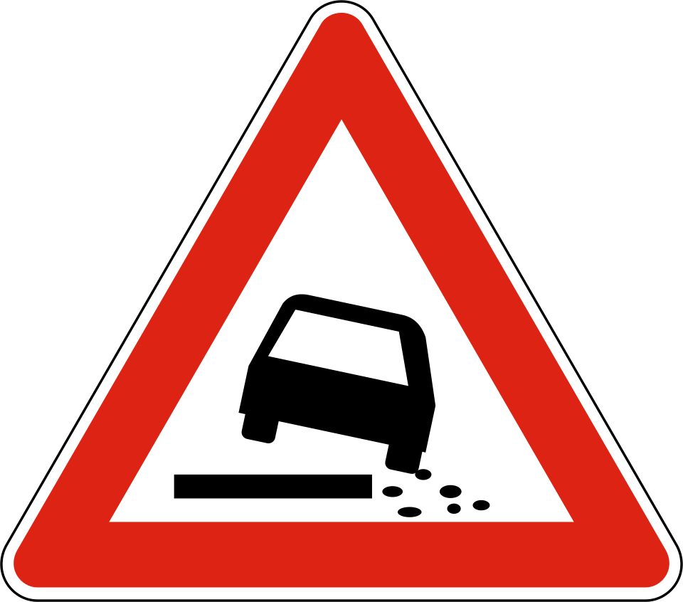 Red-bordered upright triangle; car leaning toward the right at a broken road edge with loose stones.