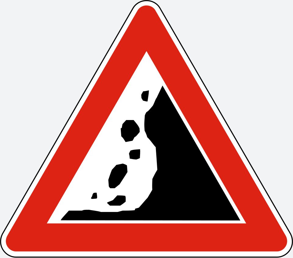 Upright white triangle with a red border; a black rock face on the right and separate rocks falling to its left.