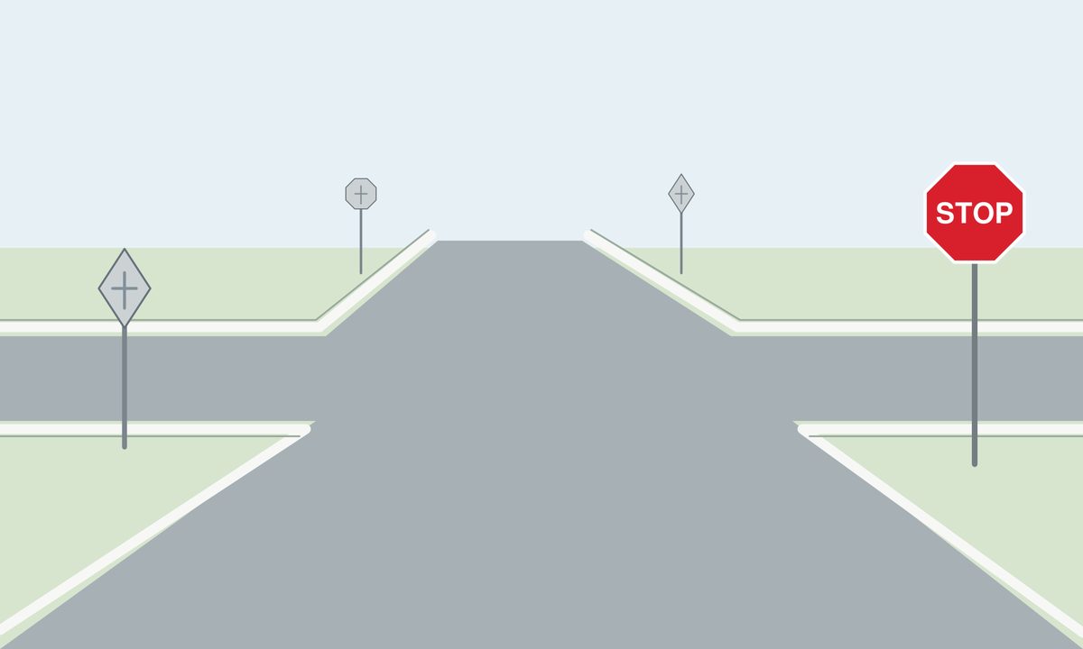Empty unmarked four-arm junction viewed from the approaching road. A red octagonal STOP sign faces the viewer on the right; three gray sign backs stand at the other approaches.