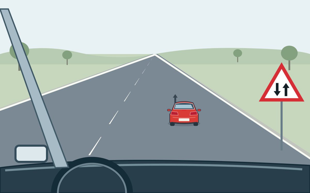 View from a car following a red car in the right lane; at the right is a white triangle with a red border and two black arrows, the left pointing down and the right pointing up.