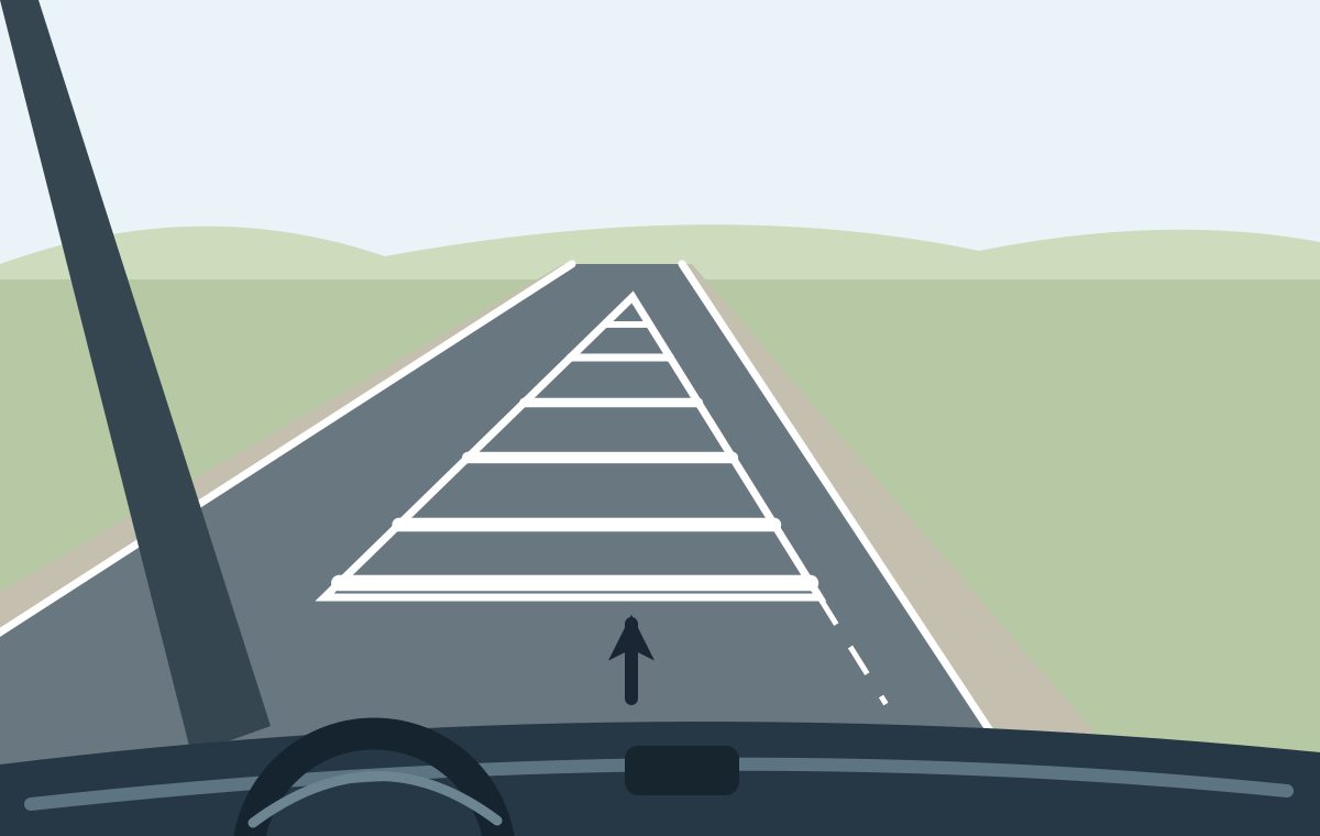 Driver view with a forward arrow towards a triangular white-hatched central area bounded by solid lines; a broken lane divider continues towards the viewer from its near-right corner.