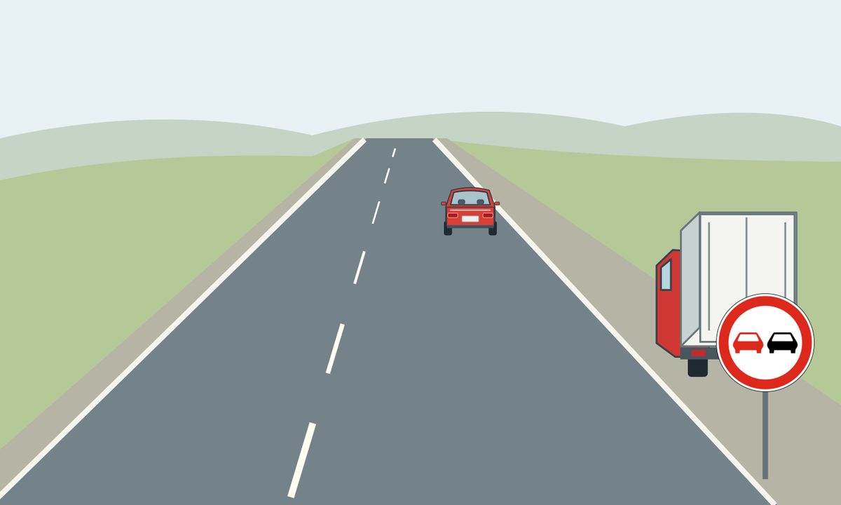 A lorry on the roadside shoulder, a red car farther ahead and a circular sign.