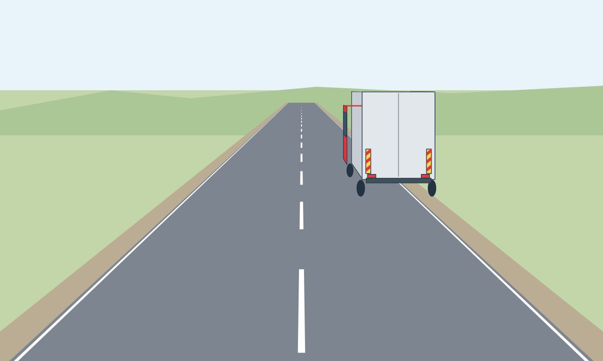 A lorry partly on a narrow roadside shoulder, beside a solid edge line.