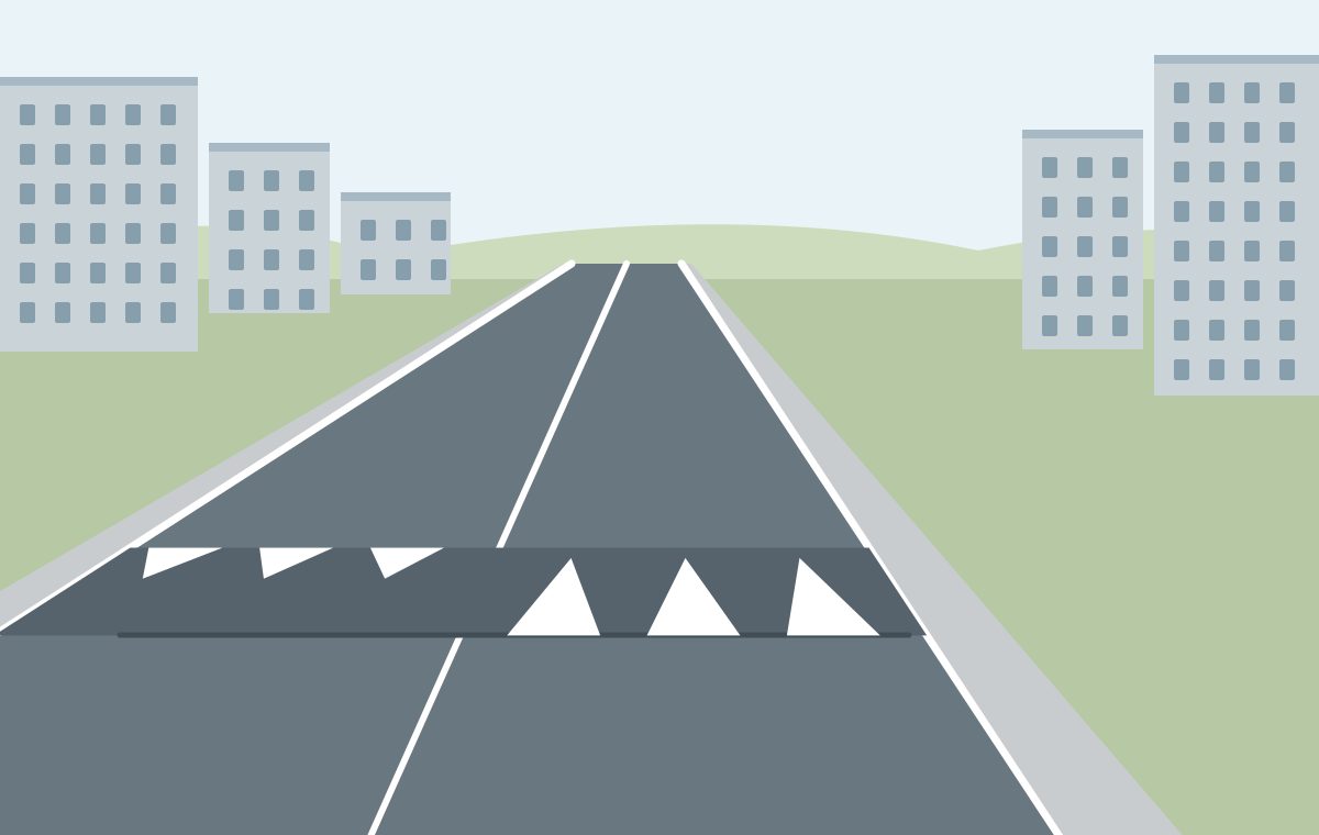 Urban road with a dark raised strip across both lanes and white triangular ramp markings facing the respective approaches.