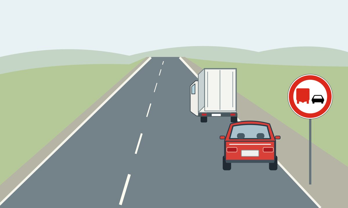 A lorry and a red car beside a rural road sign.