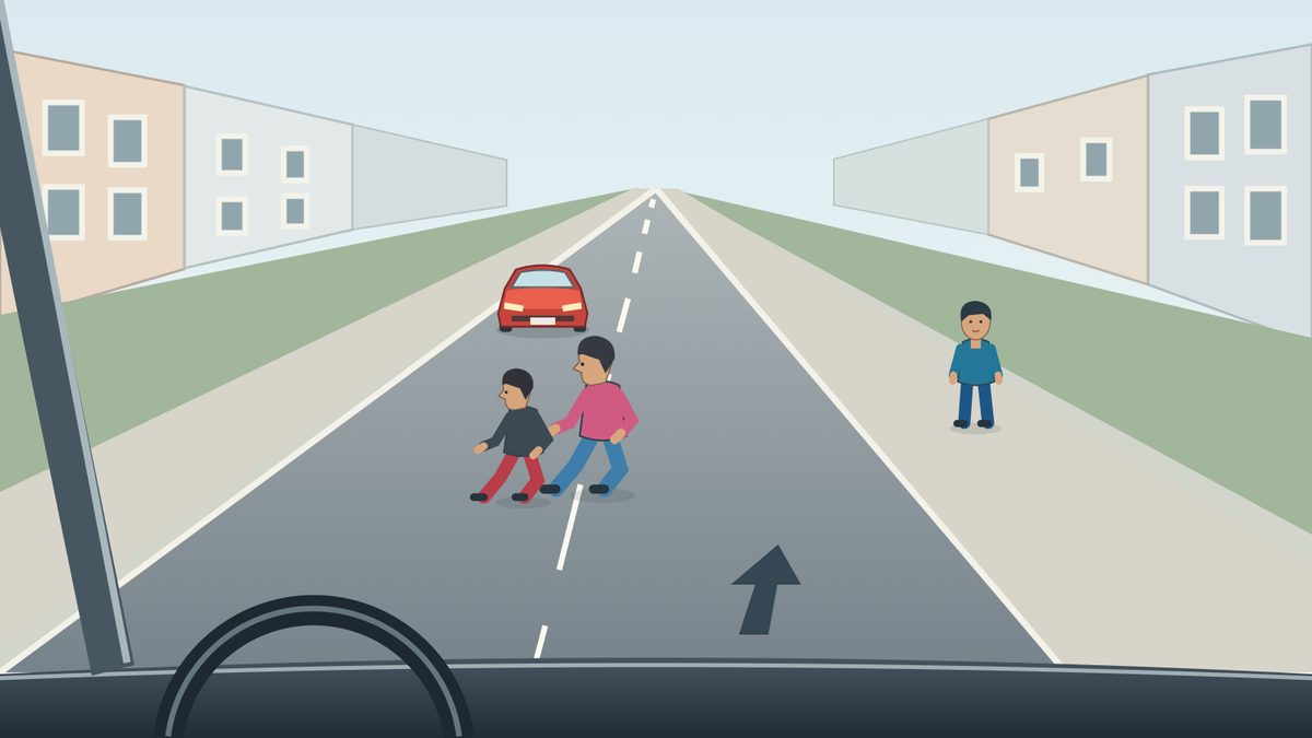 Driver view along a two-way street: two children in dark/red and pink/blue clothing walk left near the centre line; a red car approaches farther away and a third child in blue stands on the right pavement.
