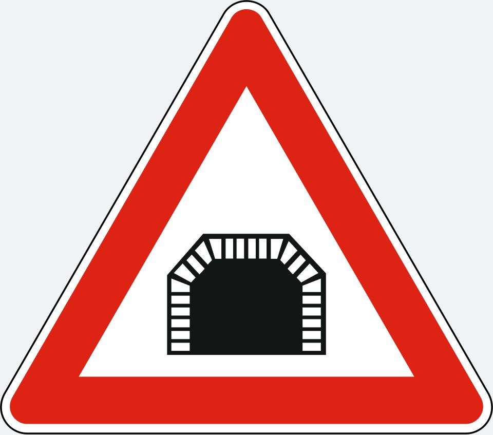 Upright white triangle with a red border; a black arched opening outlined by small rectangular blocks.
